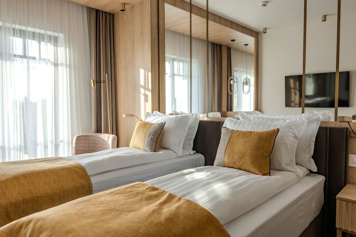 Ein Hotelzimmer mit zwei Betten, einem Fernseher und einem großen Fenster mit Vorhängen.