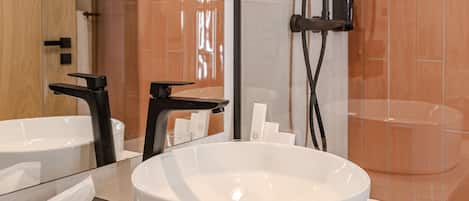Un baño moderno con un lavamanos grande blanco, un grifo negro y un cabezal de ducha de mano.