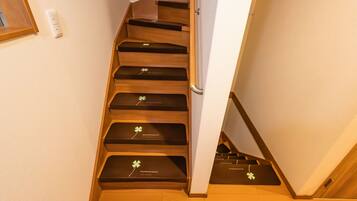 A wooden staircase with black steps and a white wall.