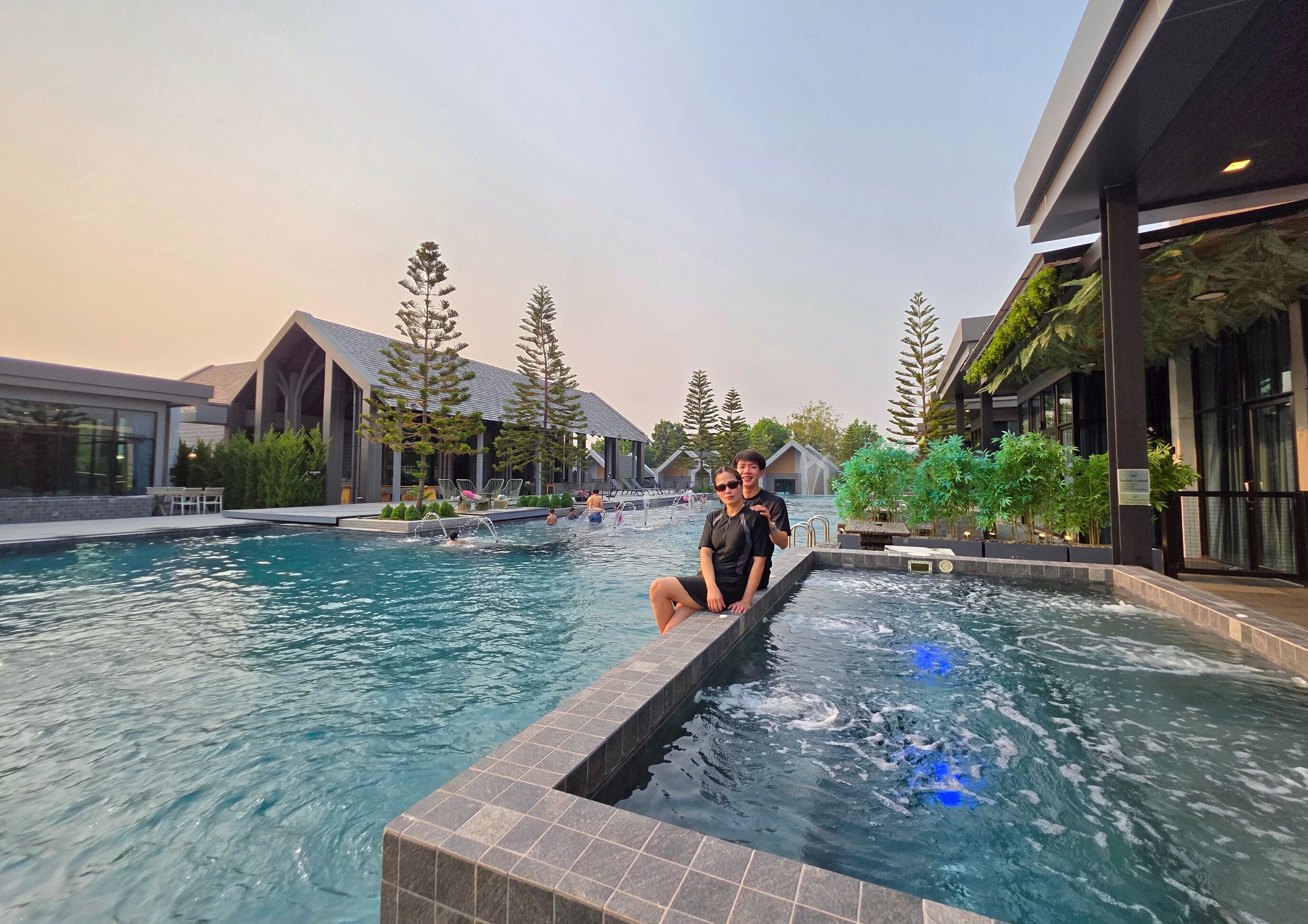Un espace piscine avec un bâtiment moderne, des sièges et des arbres.