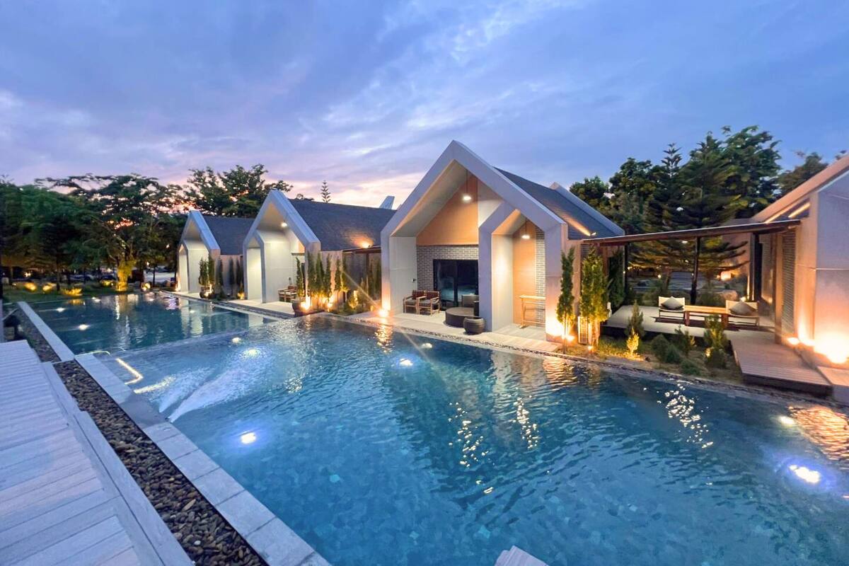 Een modern resort met een groot zwembad, geschakelde villa's met buiten zitplaatsen en een aangelegde tuin.