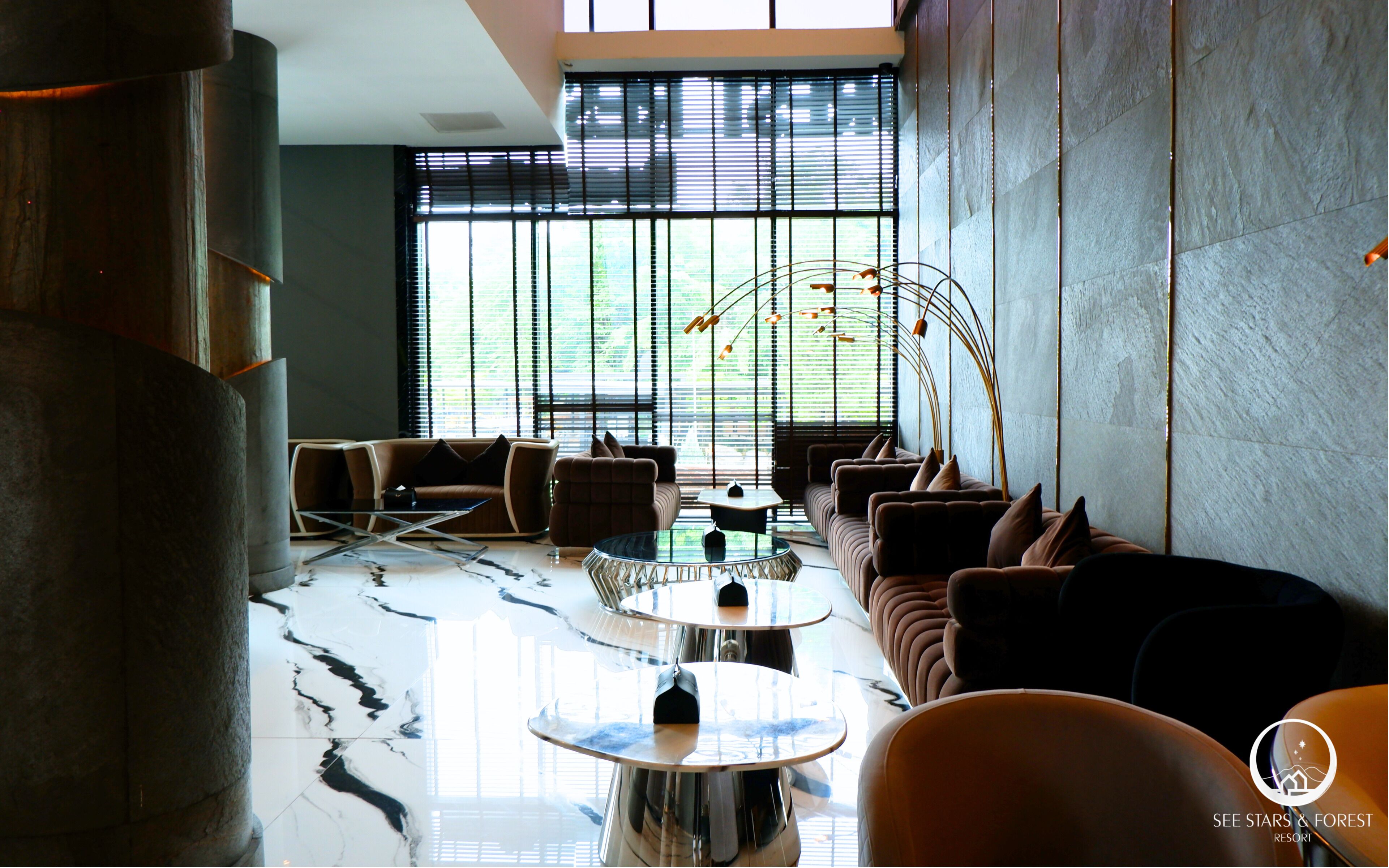 A modern lounge with a marble floor, leather sofas, and a unique curved light fixture.