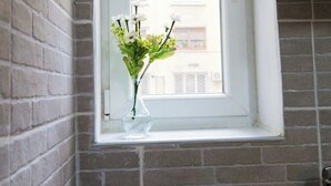 Eine Küche mit Gaskochfeld, einem Fenster mit Blick auf Gebäude und einer Blumenvase auf der Fensterbank.