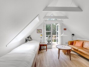 Une chambre de style loft moderne, avec un plafond en pente, une grande fenêtre, un lit, un canapé et une petite table.