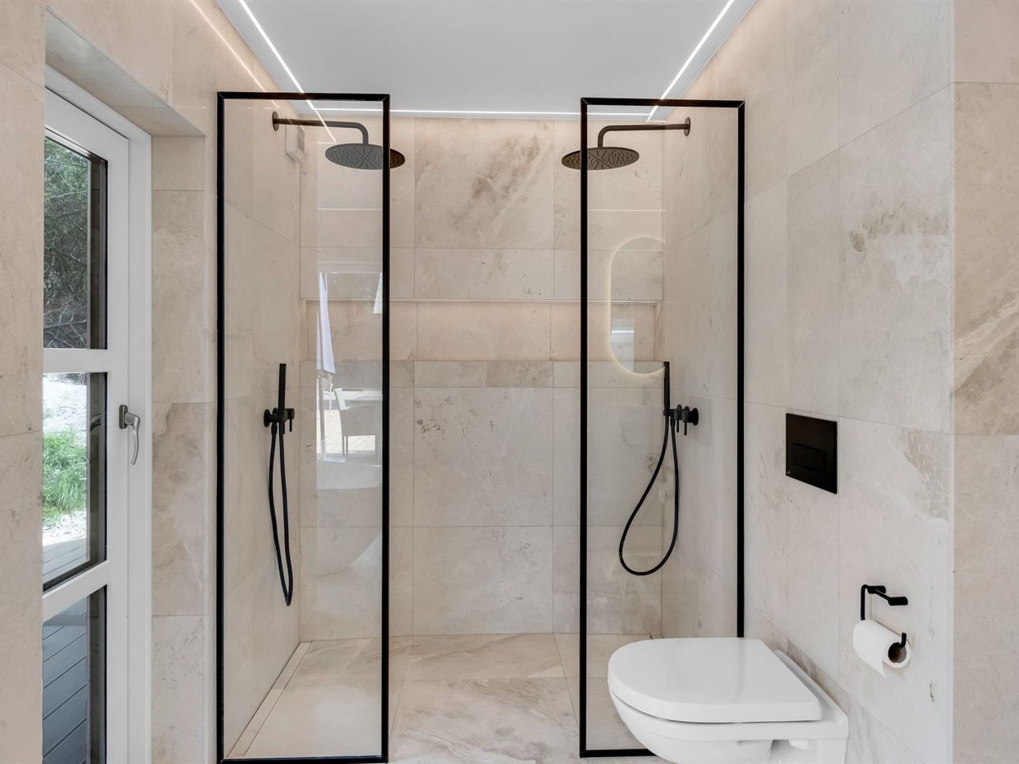 Une salle de bain moderne dotée d’une douche à parois de verre, de toilettes et d’un porte-serviettes.