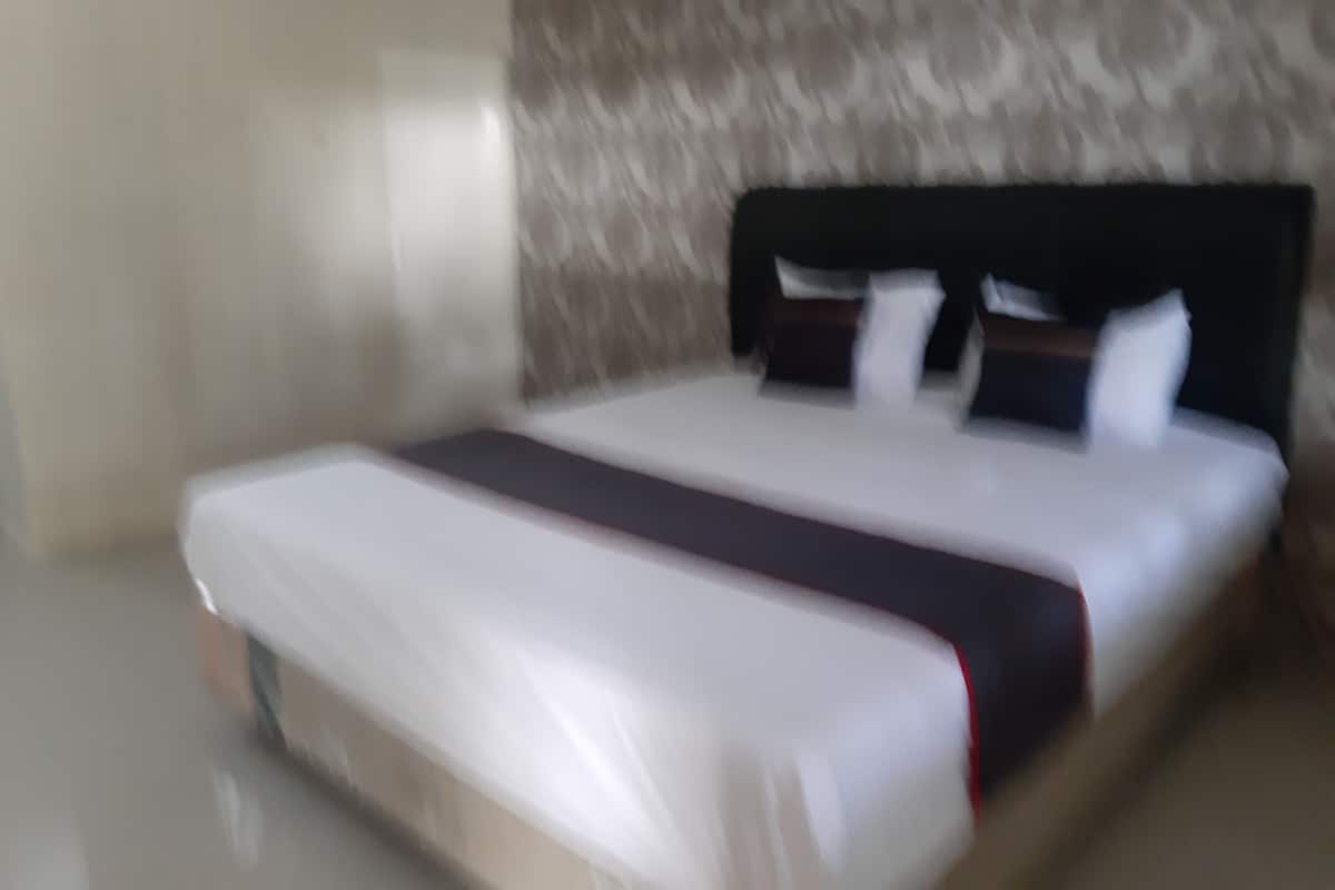 A bed with a white mattress and a dark headboard.