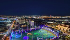 A nighttime cityscape with illuminated buildings and a large, open plaza with circular light installations. - MGM Signature-28-820 1Br 2Ba F1 Pits View Balcony (Las Vegas)