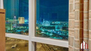 A view from a window overlooking a cityscape at night, featuring illuminated buildings and a prominent dome structure. - MGM Signature-28-820 1Br 2Ba F1 Pits View Balcony (Las Vegas)