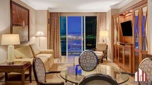 A hotel room with a large sliding glass door leading to a city view, a sofa, a glass coffee table, and a television. - MGM Signature-28-820 1Br 2Ba F1 Pits View Balcony (Las Vegas)