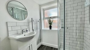 Un baño moderno con lavamanos blanco, espejo y paredes con azulejos.