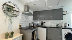 Una cocina moderna con armarios grises, horno integrado, lavavajillas y microondas.