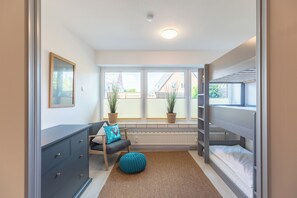 Cozy bedroom with a bunk bed, dresser, and comfortable seating area.