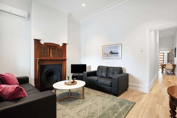 A living room with a fireplace, a sofa, a television, and a painting on the wall.