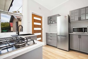 A modern kitchen with a gas stove, stainless steel appliances, and grey cabinetry.