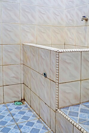Un coin de salle de bain avec des carreaux beiges aux murs et un sol recouvert de carreaux bleus.
