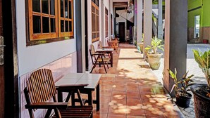A covered outdoor seating area with wooden tables and chairs, potted plants, and a tiled floor. - Hotel O Nusantara (Banyuwangi)
