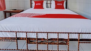 A bed with a metal frame, white bedding, and two red pillows with the word "OYO" on them. - Hotel O Nusantara (Banyuwangi)