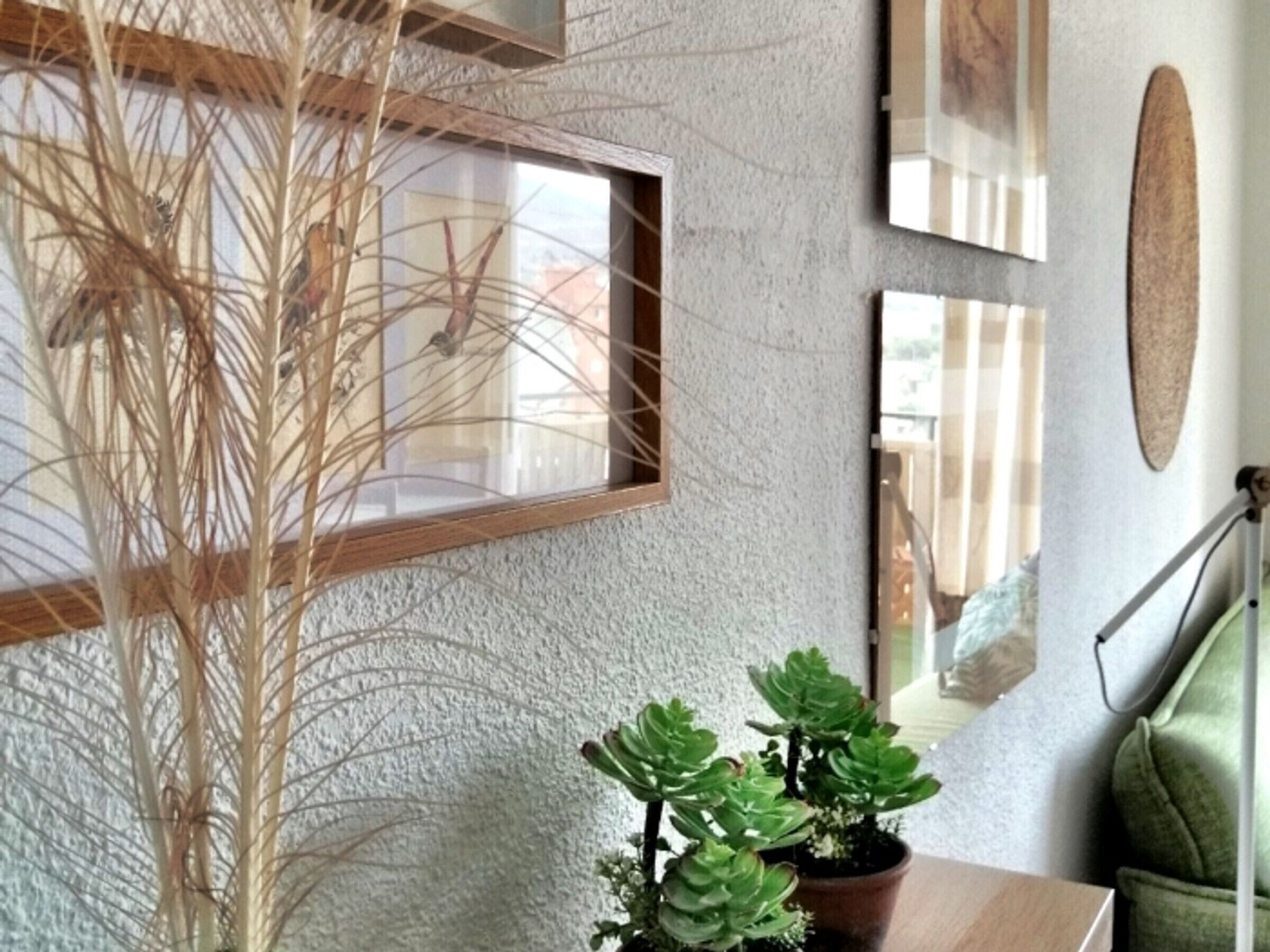 Una habitación con pared texturizada, repisa de madera, planta en maceta y un cuadro enmarcado.