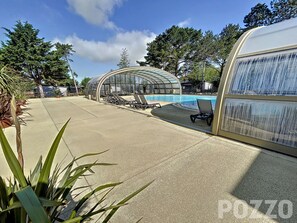 Un área de piscina con sillones de descanso y una estructura de vidrio.