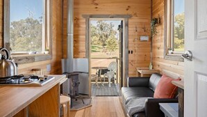 Ein gemütliches Holzhaus mit einer Küchenzeile, einem Essbereich und einer Sitzecke mit Blick ins Freie.