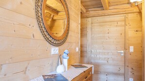 A wooden interior with a wooden bench, a mirror, and a small statue.