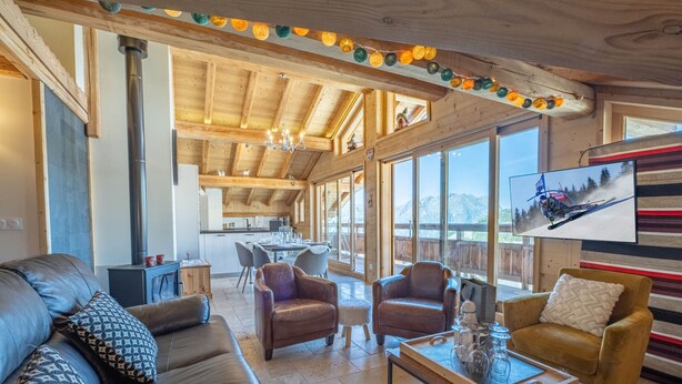 A spacious living area with a wooden ceiling, a sofa, armchairs, and a coffee table.