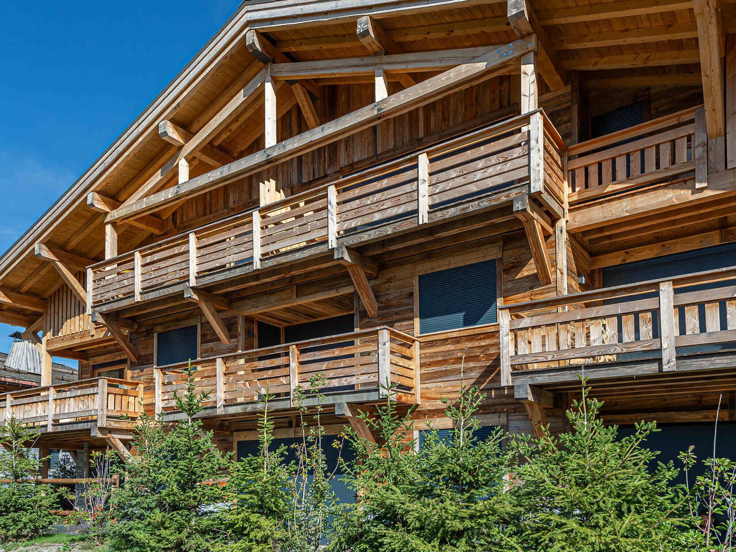 A multi-story wooden building with balconies and large windows.