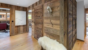 Una stanza con pareti rivestite in legno, una soffice panca bianca e una testa di cervo appesa al muro.