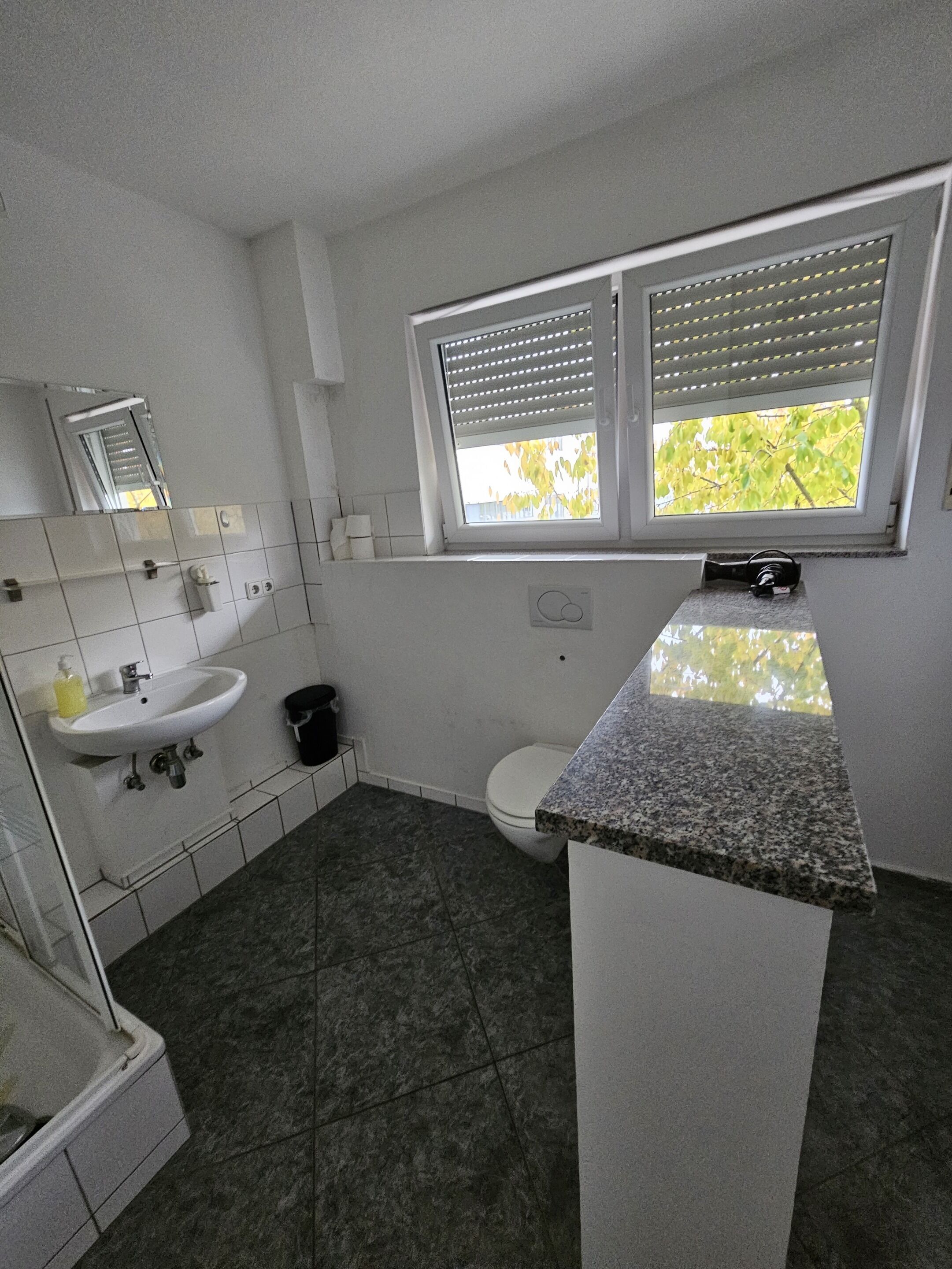 A small, clean bathroom with a sink, toilet, and window.