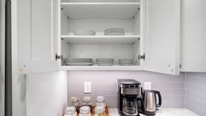 Una cocina con armarios blancos, una cafetera y frascos de especias en la encimera.