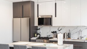 A modern kitchen with a central island, stainless steel appliances, and a marble backsplash.