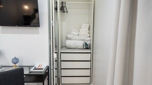 A compact room with a bed, a desk with a lamp, and a TV on the wall.
