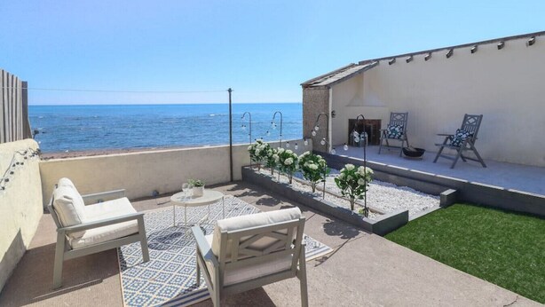 Une terrasse avec vue sur la mer, des sièges extérieurs et un petit jardin.