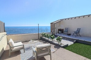 A terrace with a view of the sea, outdoor seating, and a small garden area.
