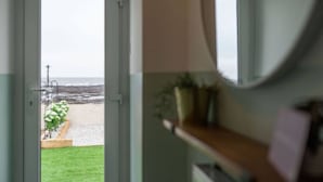 Une porte-fenêtre donnant sur un balcon avec vue sur la plage et l’océan.