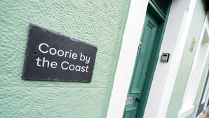 Une enseigne sur un bâtiment portant l’inscription « Coorie by the Coast ».