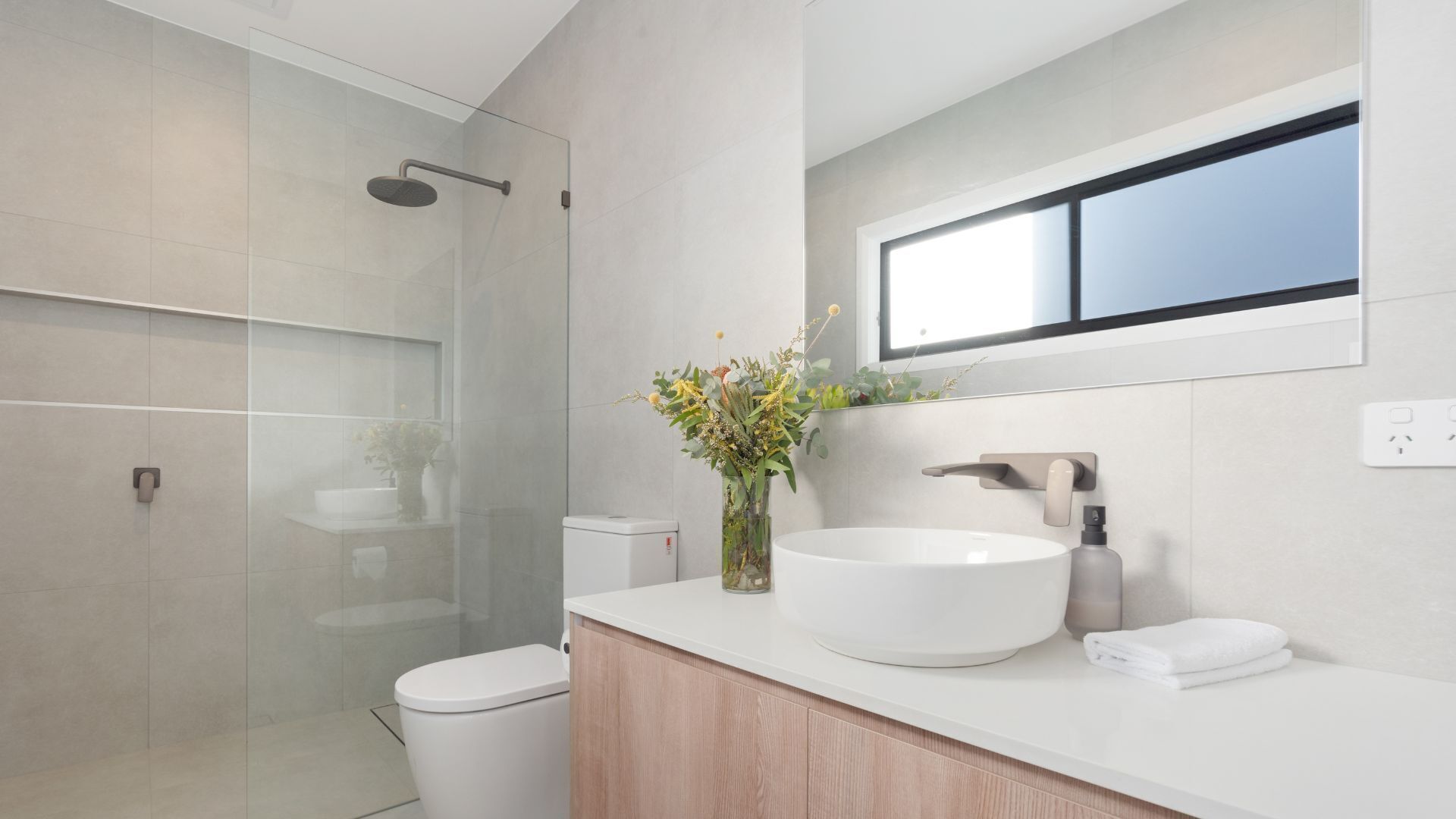 A modern bathroom with a glass shower enclosure, a white sink, and a mirror above the sink.