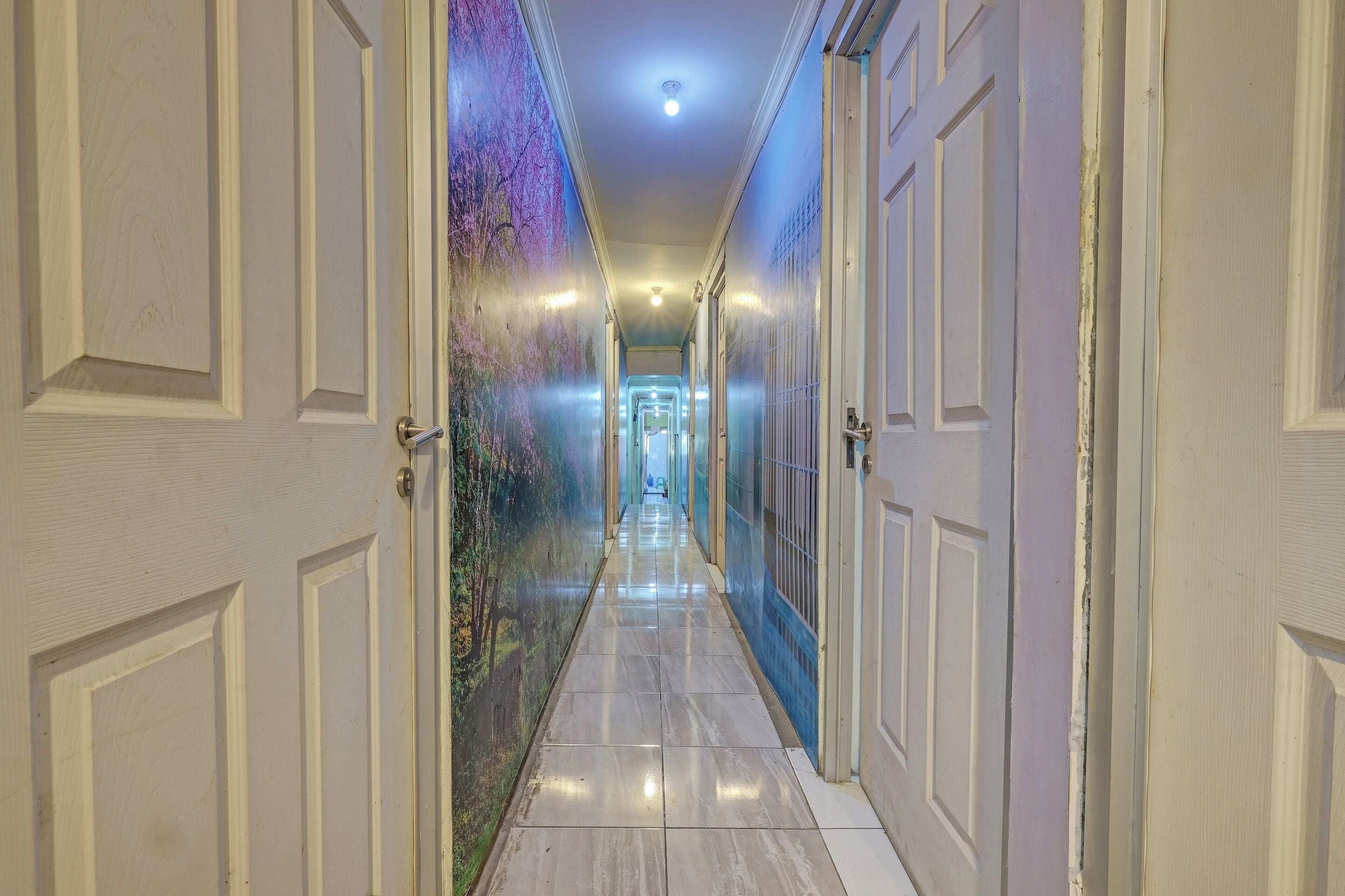 A hallway with doors on both sides, leading to a bright room at the end.