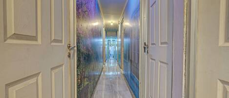 A hallway with doors on both sides, leading to a bright room at the end.