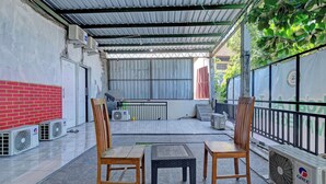 An outdoor seating area with chairs and a table, air conditioning units, and a covered patio. - OYO Life 92877 Hotel Rainbow 7296 (Semarang)