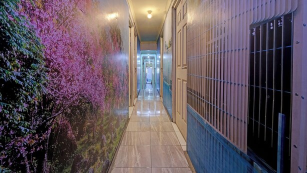 A corridor with a tiled floor, a mural on the left, and a metal gate on the right. - OYO Life 92877 Hotel Rainbow 7296 (Semarang)