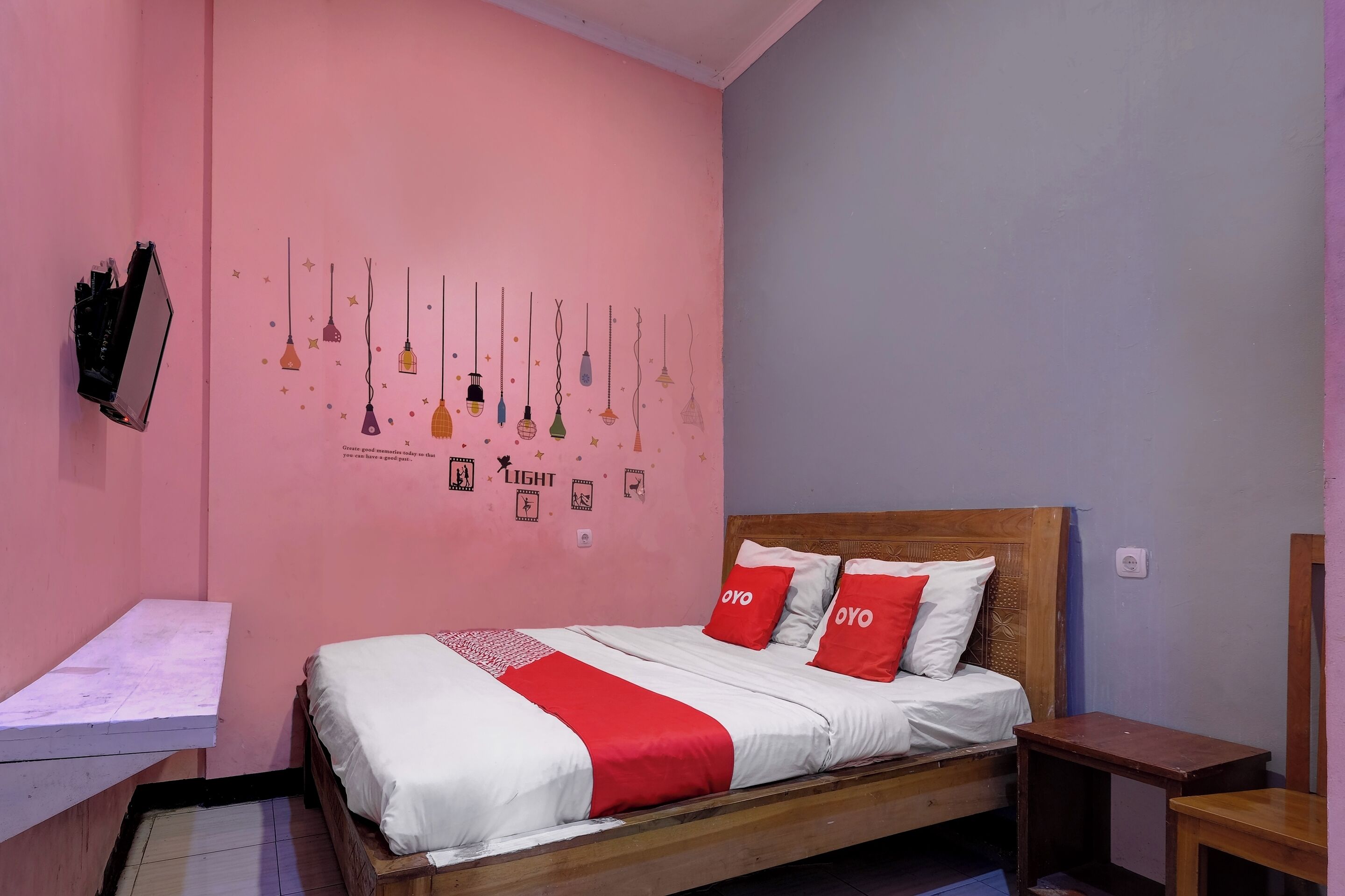 A single-bed room with a wooden headboard, a bedside table, and a small desk with a chair.