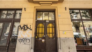 Um edifício com vários andares, entrada central, janelas amplas e varanda.