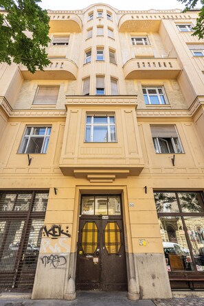A multi-story building with a central entrance, large windows, and a balcony.