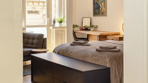 Quarto com cama beliche, escrivaninha, cadeira, banqueta e um quadro na parede.