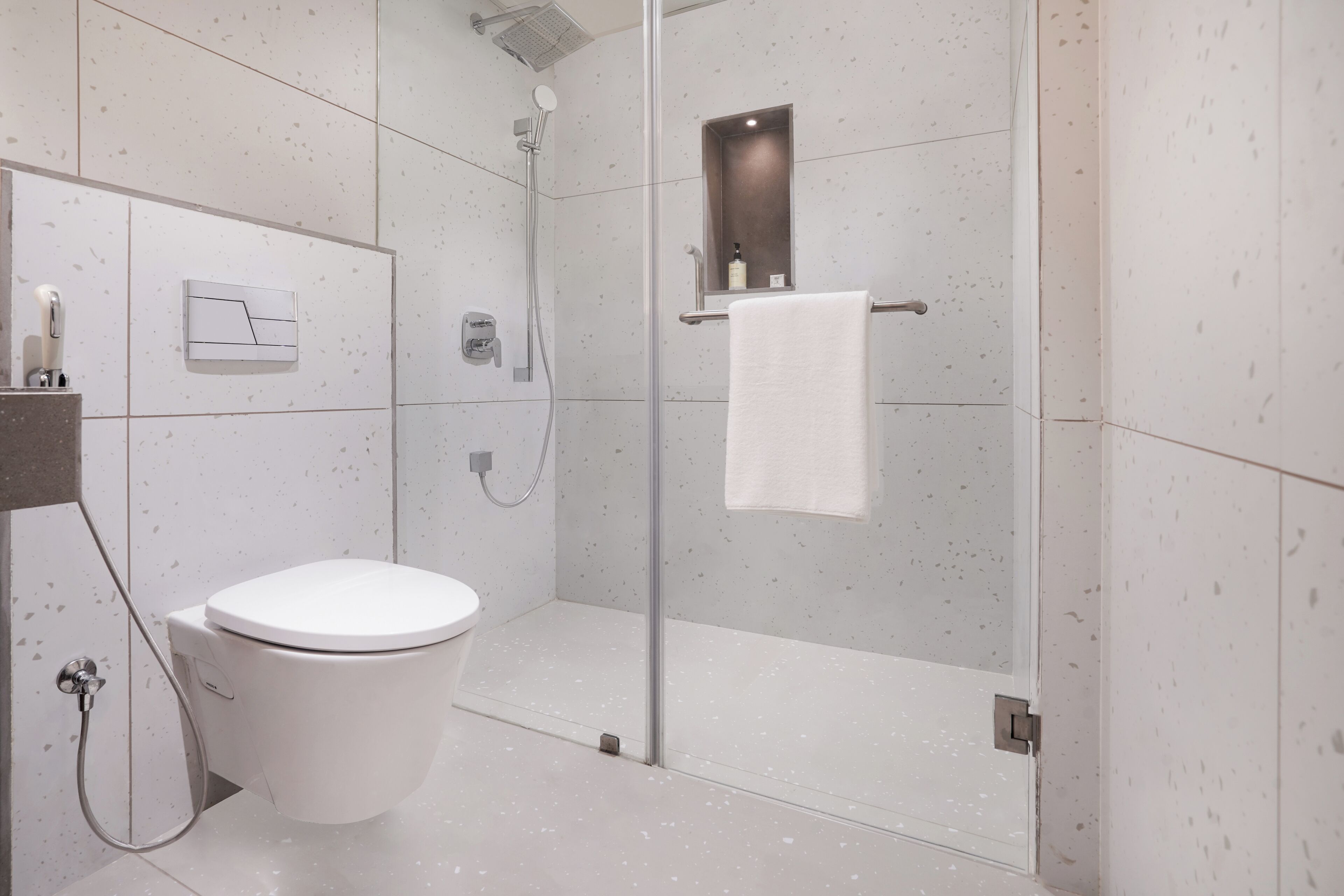 A modern bathroom with a toilet, a shower enclosure, and a towel rack.