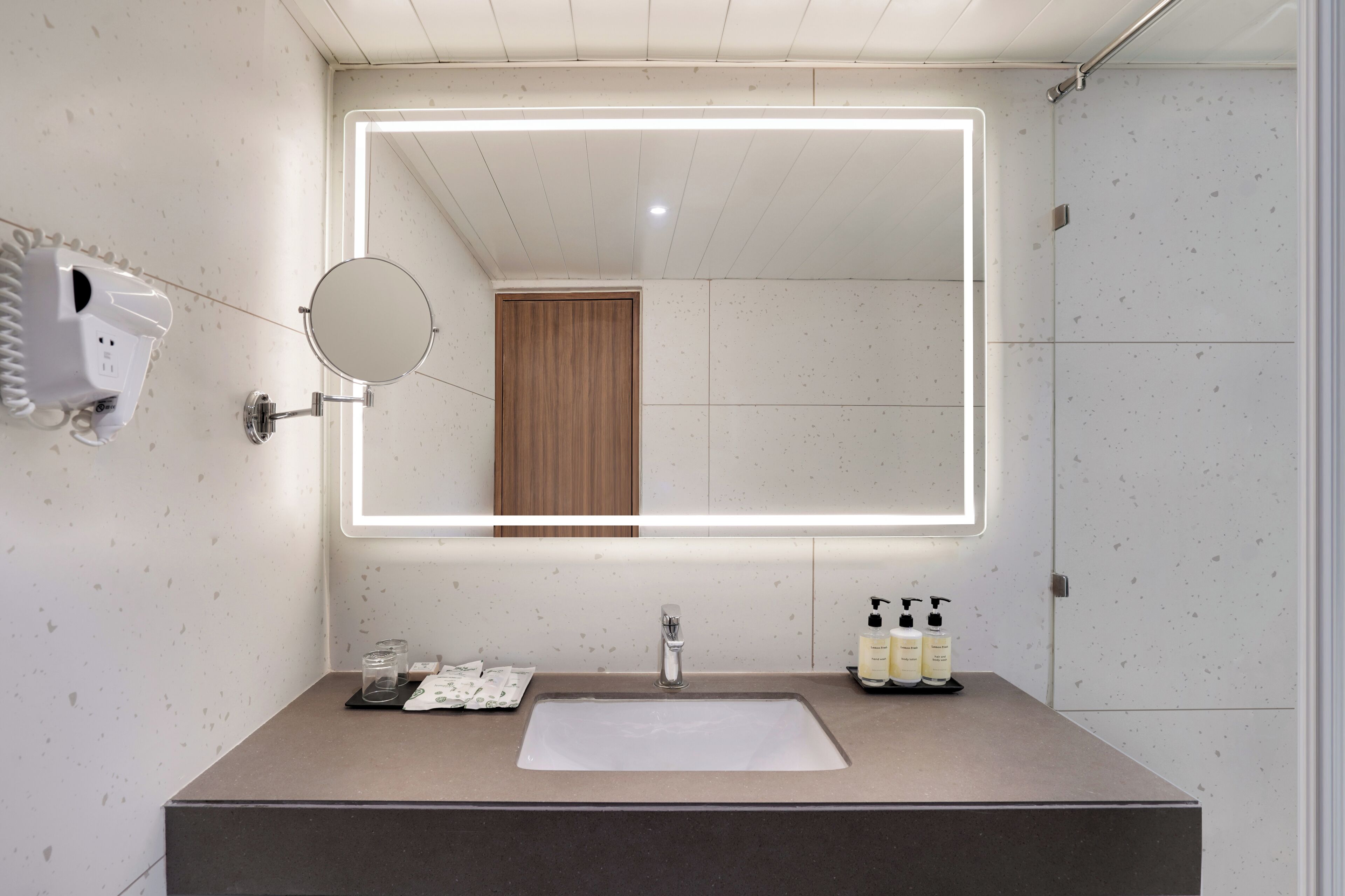 A modern bathroom with a large mirror, a sink, and a shower area.