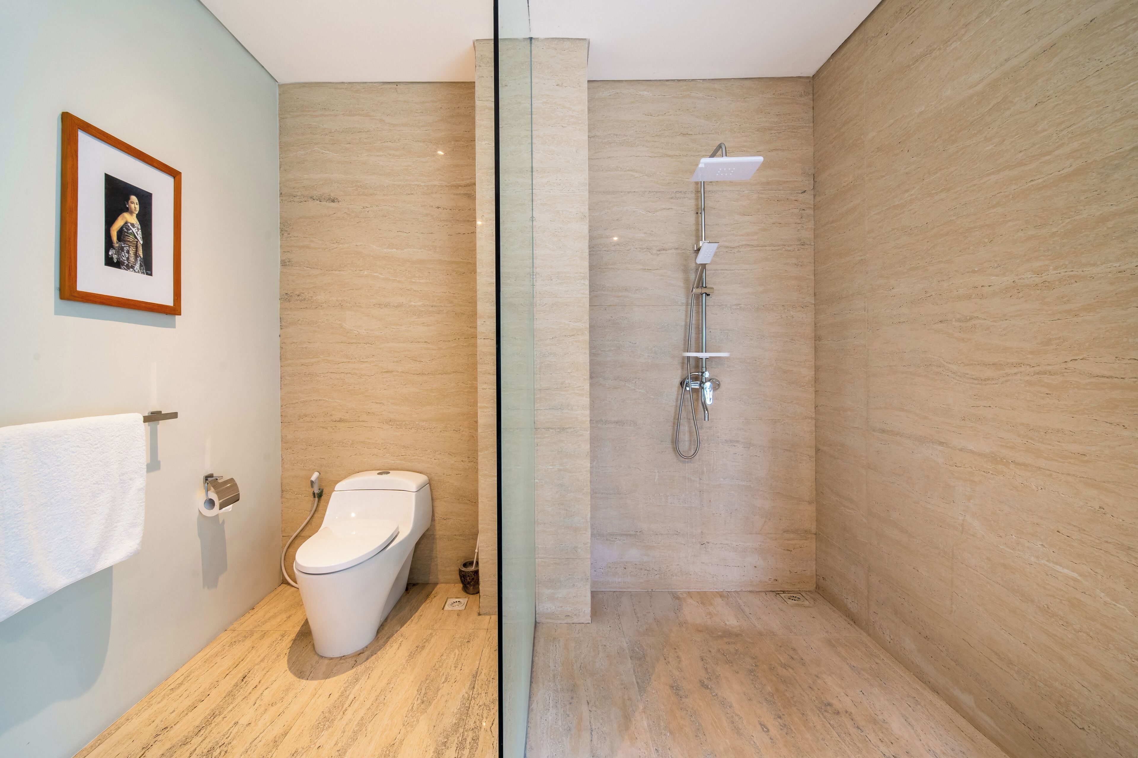 Une salle de bain moderne avec des toilettes, une douche et une photo encadrée accrochée au mur.