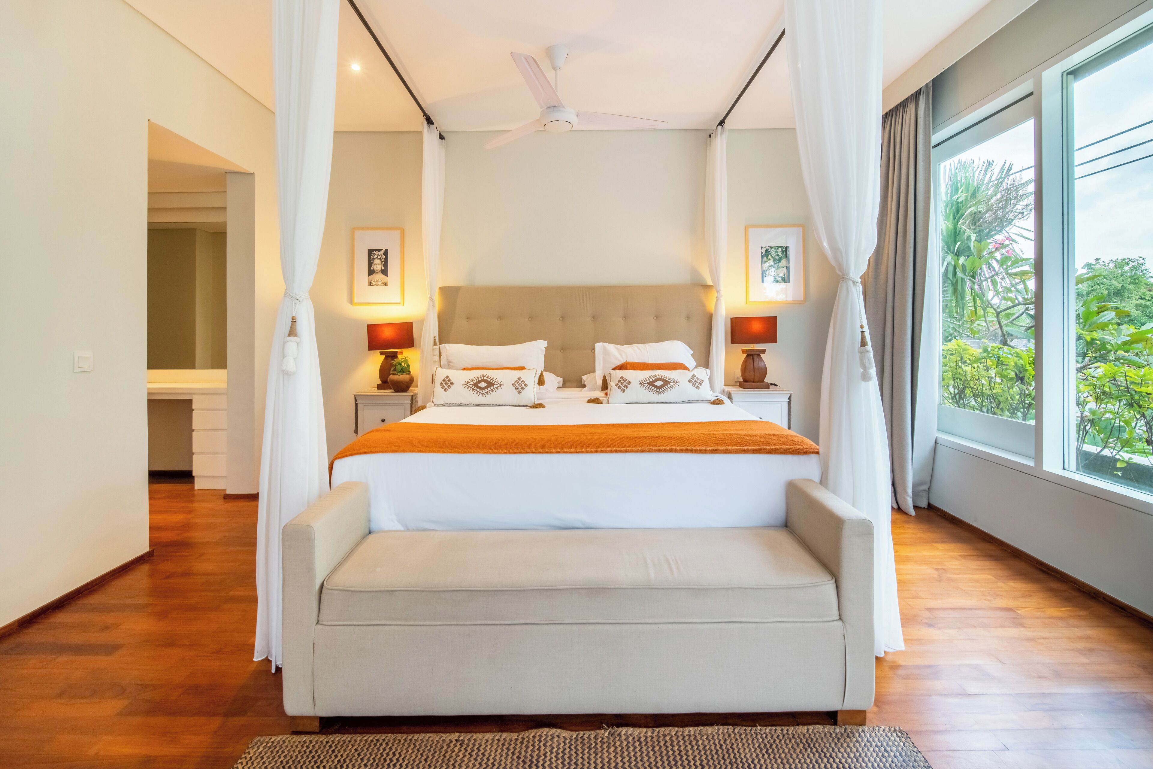 A spacious bedroom with a large bed, a canopy, and a view of greenery outside.