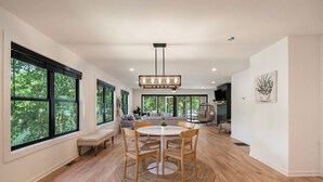 A spacious dining area with a round table, wooden chairs, and a hanging light fixture. - Tranquille Resort (Hiawassee)